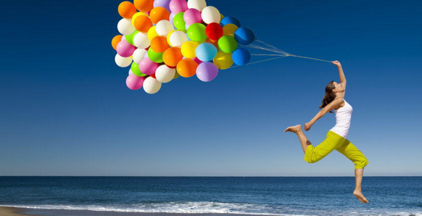 Femme qui saute avec des ballons à la main