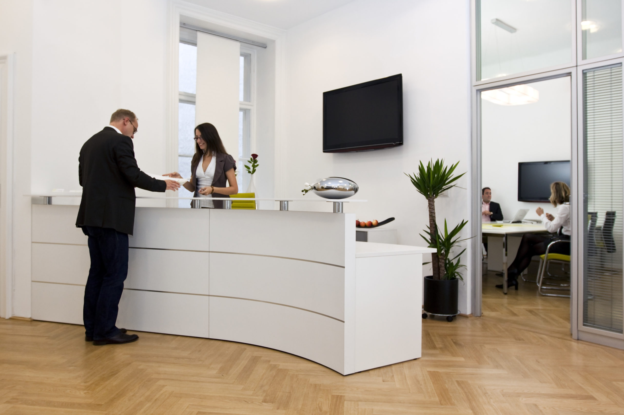 homme discutant avant la secrétaire d'accueil de l'entreprise