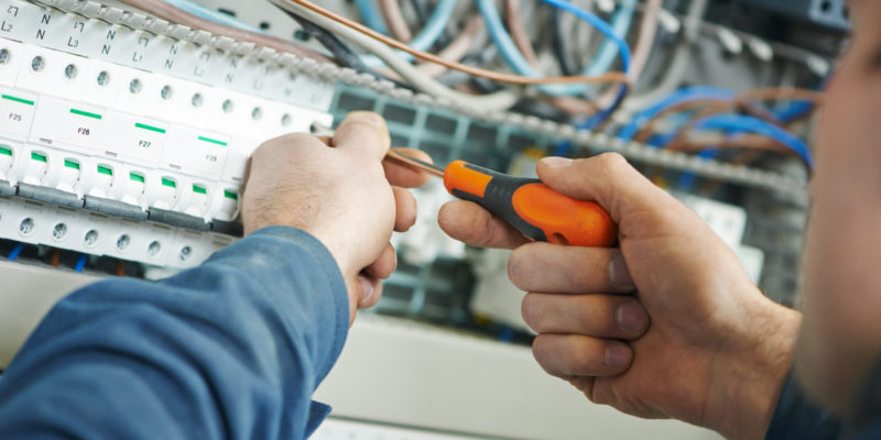 electrician work les mains d'un électricien avec un tournevis serrent l'équipement de l'actionneur électrique de commutation dans la boîte à fusibles