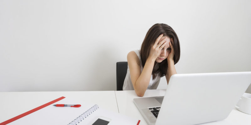 Stressed businesswoman with laptop at desk in office employée stressée devant son poste de travail